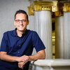 Professor Cisneros posing in front of some marble columns.